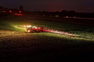 Landbouwvoertuig met Nordic Lights werklampen werkt 's nachts op een veld.